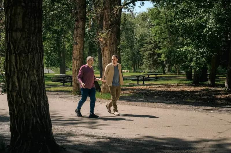 Two people walking side by side on a wooded trail