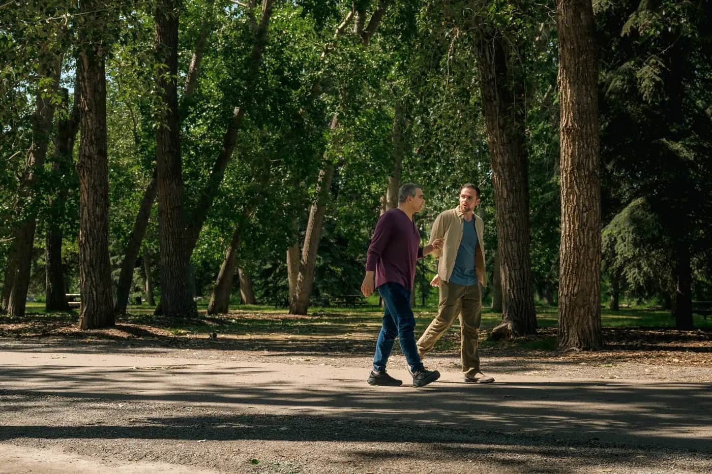 Two people walking and talking along a tree-lined pathway in a Calgary park