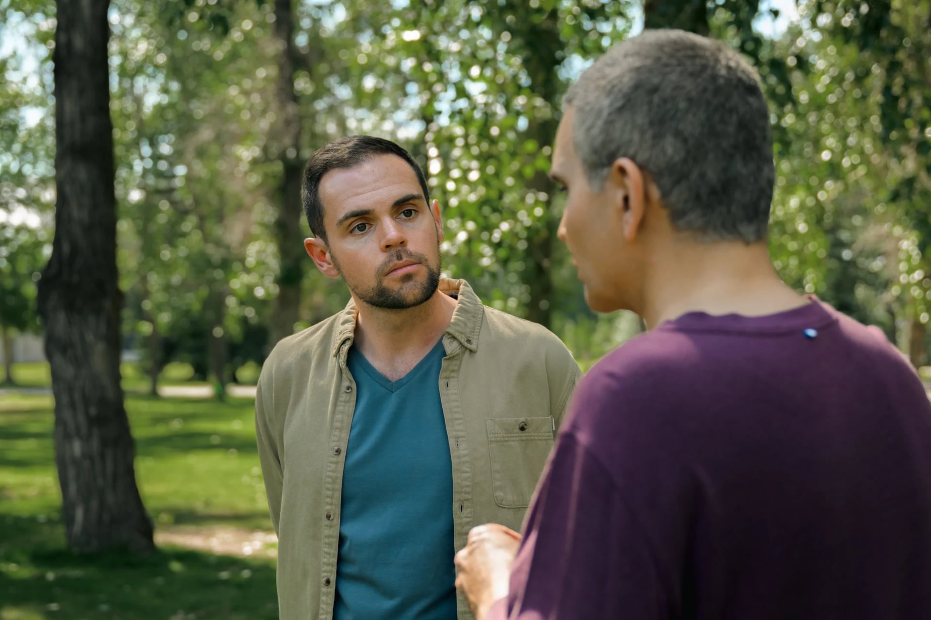 Two men in conversation, standing in a leafy Calgary park