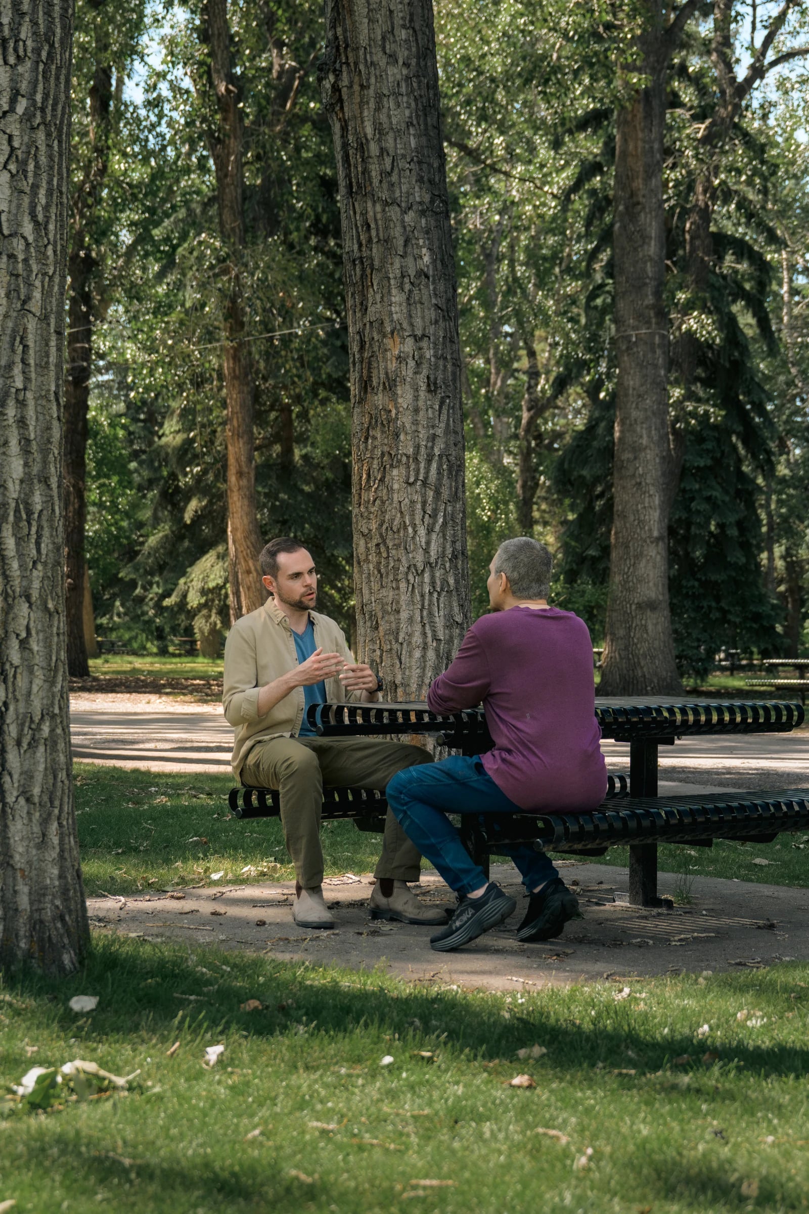 Michael Snow in conversation with a client at a picnic table in a Calgary park